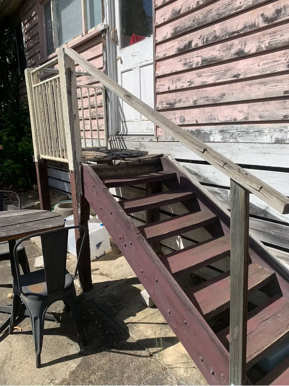 Old back steps with worn treads and a loose handrail