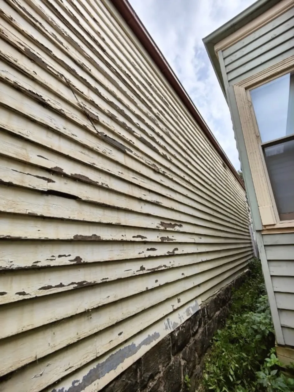 Old weatherboards with flaking paint and split boards